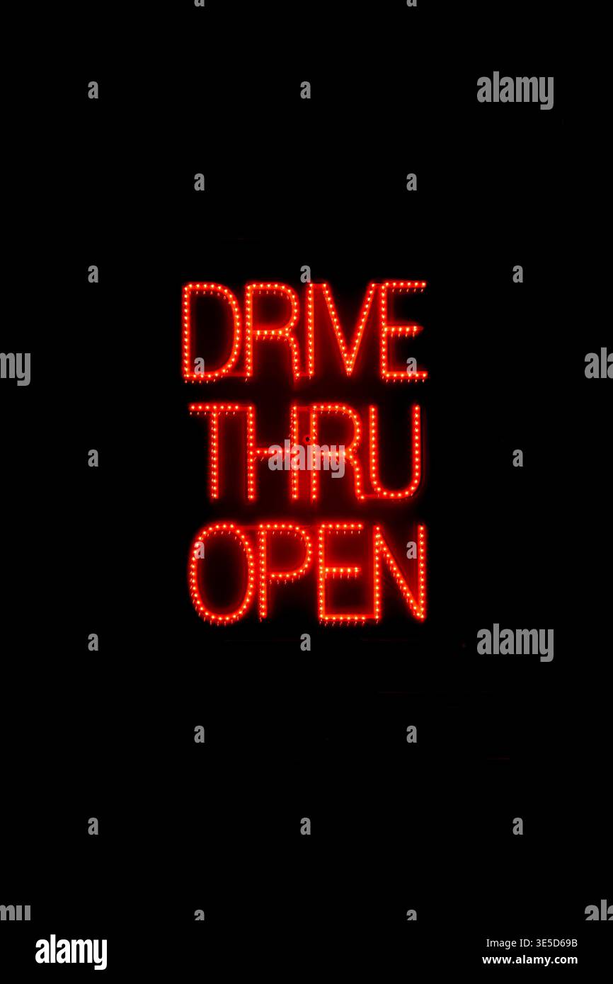 Nachts beleuchtetes Schild im Fenster eines Fast-Food-Restaurants, das die Gäste darauf hinweist, dass das Drive-Thru-Fenster geöffnet ist. Stockfoto