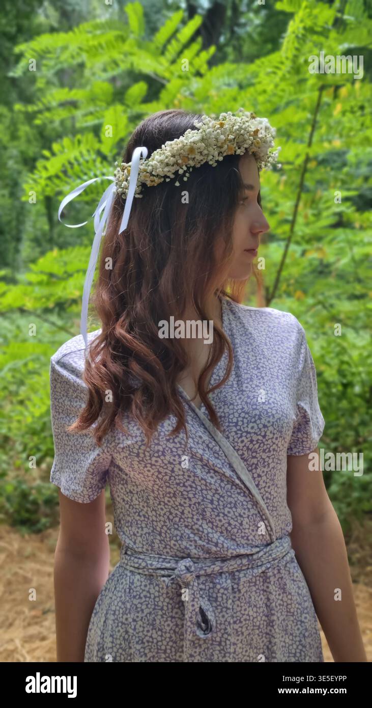 Junge Frau mit Blumenkranz, die im Wald steht Stockfoto