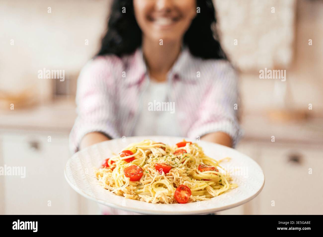 Frau, die tagsüber in der Küche Pasta mit Tomaten hält Stockfoto