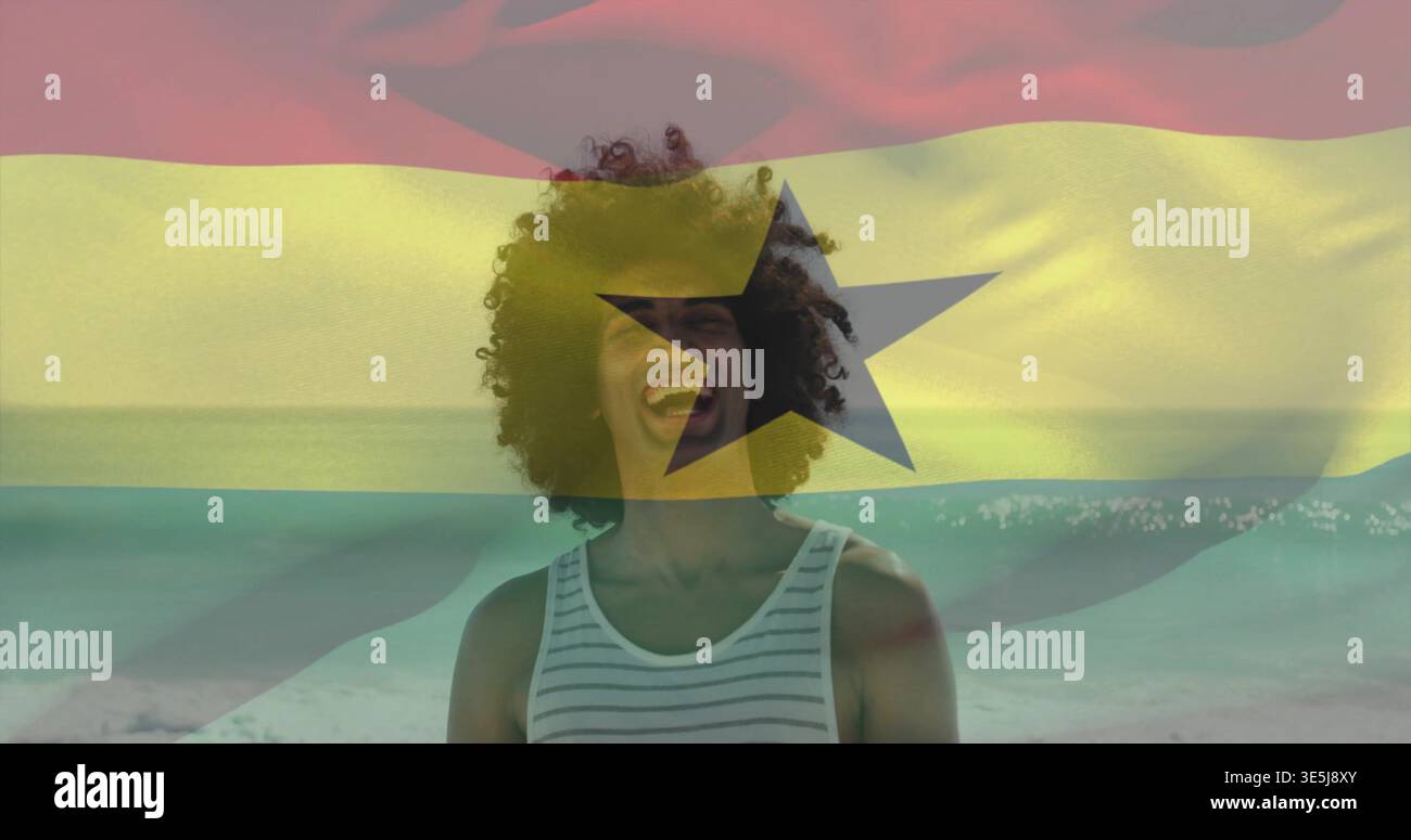Lachender Mann in gestreiftem Tanktop am Wasserrand, mit Ghana-Flagge und schwarzem Stern Stockfoto