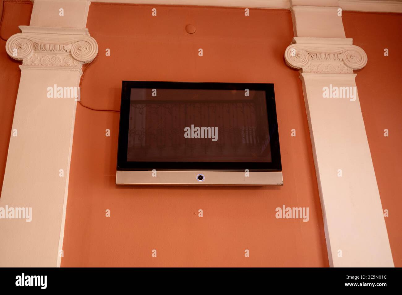 Moderner Fernseher an einer Wand zwischen klassischen Säulen. Fusion neuer Technologien Stockfoto