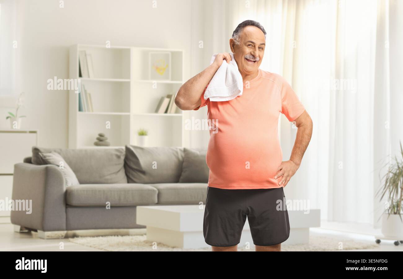 Reifer Mann in einem Sport-T-Shirt und Shorts, der zu Hause ein Handtuch hält Stockfoto