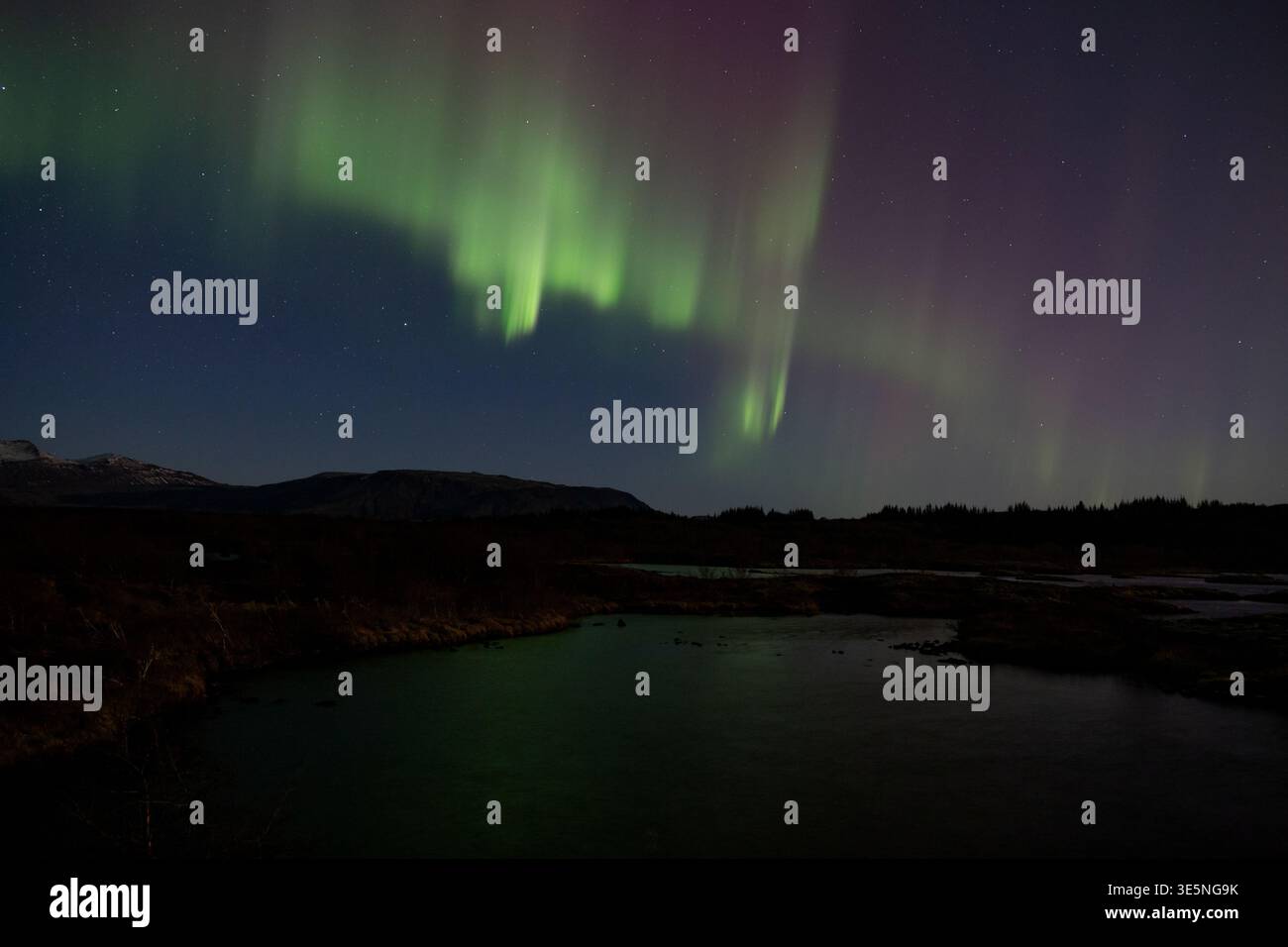 Starke rote und grüne aurora Borealis, die sich im Thingvellir-See spiegeln Stockfoto