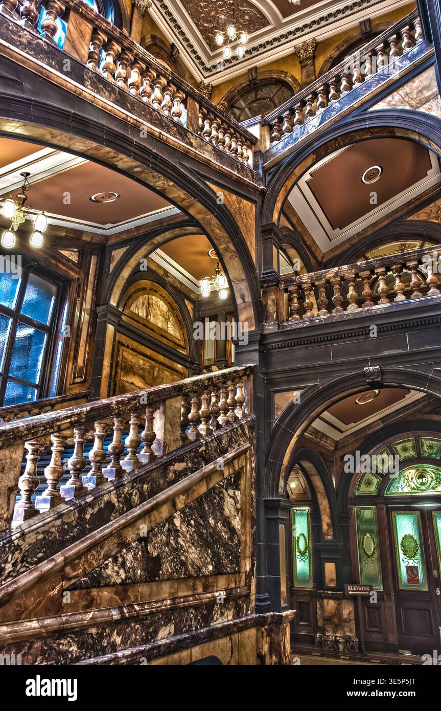 Reich verzierte Marmortreppe und geschnitzte Brüstungen füllen das Innere der historischen Stadtkammern mit großen Bögen, warmer Beleuchtung und detaillierter Deckendekoration. Stockfoto