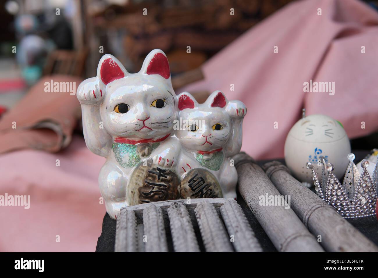 Ein Paar traditioneller weißer Keramik Maneki Neko-Katzen mit roten Ohren und grünen Kragen, die koban-Münzen halten, die Glück und Glück repräsentieren Stockfoto