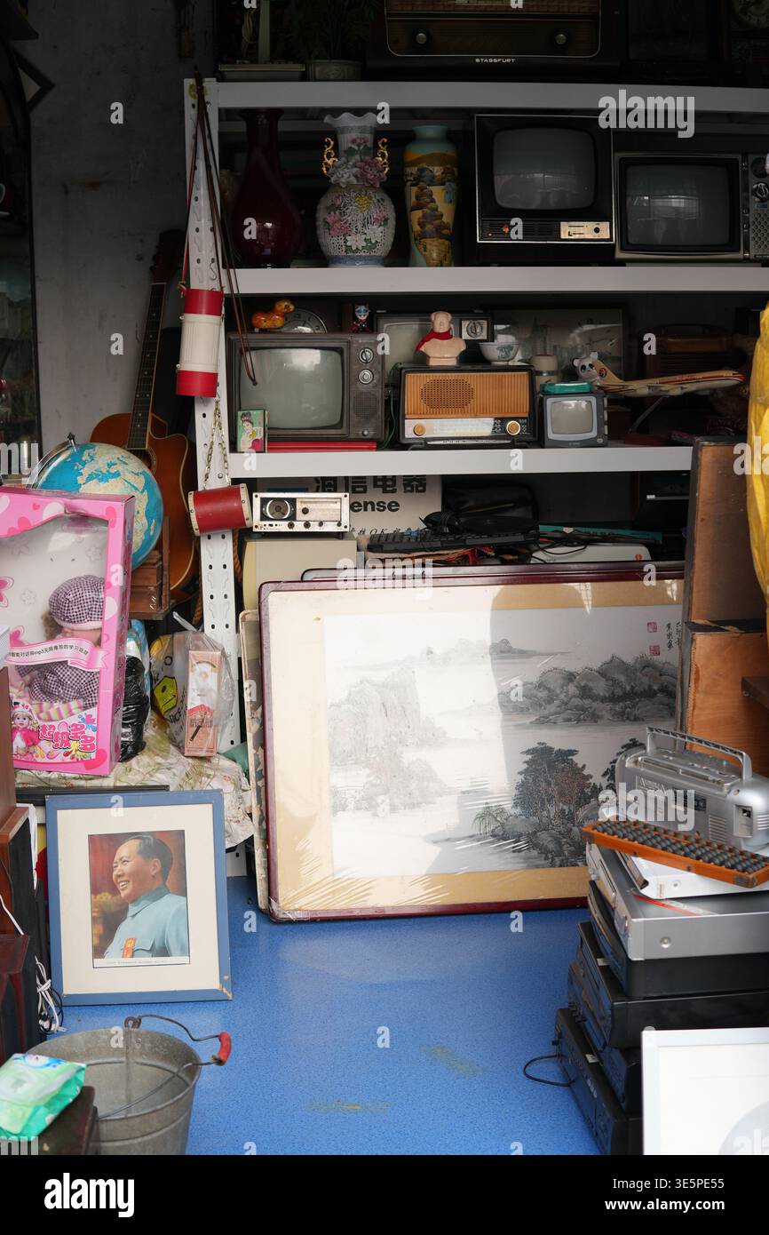 Qingdao 1. März 2026 überfüllter Raum mit einer Sammlung von Vintage-Fernsehern, Radios und einem gerahmten Mao Zedong-Porträt, was einen starken Sinn weckt Stockfoto