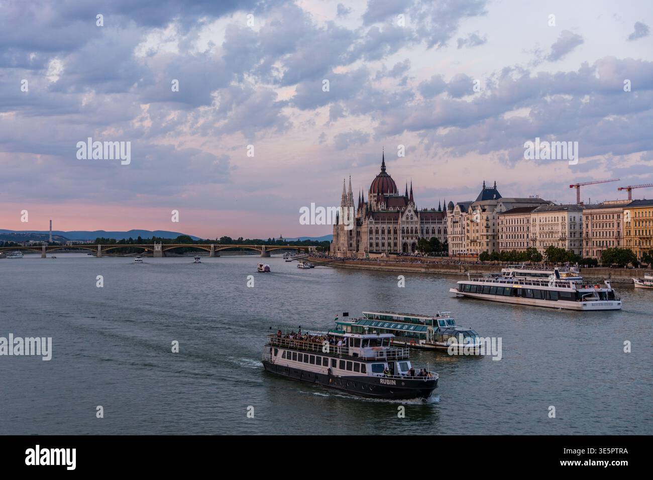 BUDAPEST, UNGARN - 7. September 2025: Bootstouren auf der Donau in der Dämmerung mit dem ungarischen Parlament und der Margaretenbrücke dahinter. Stockfoto