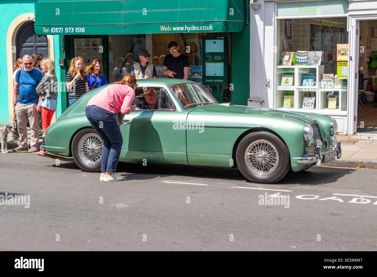 Klassischer grüner Aston Martin DB2 4 Oldtimer, der auf einer Straße in Bristol geparkt ist, während die Leute ihn bewundern Stockfoto