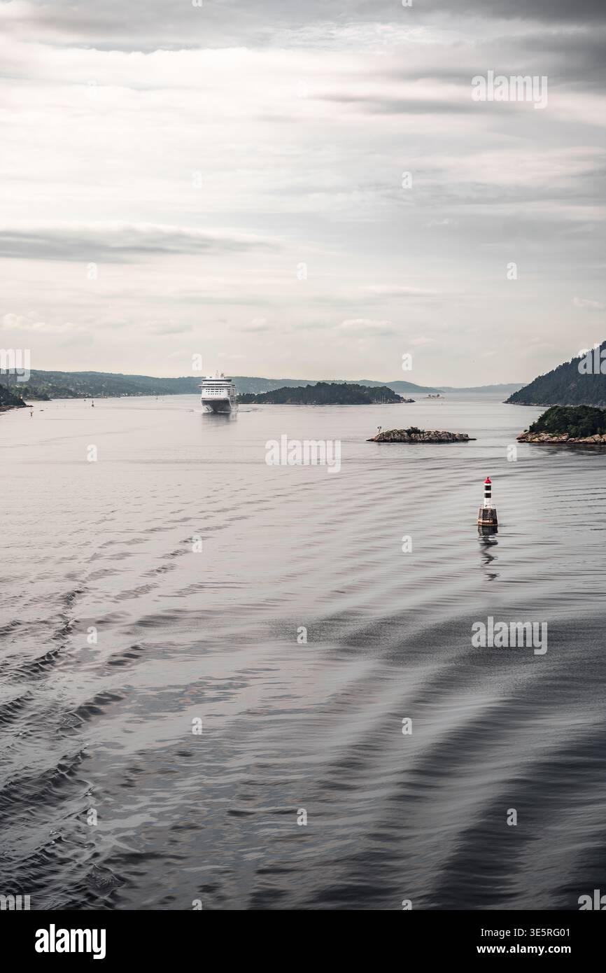 Blick auf den Oslofjord. Leuchtturm der Navigationspatboje im Vordergrund mit einem Kreuzfahrtschiff im Hintergrund. Sommerreisen in Skandinavien Stockfoto