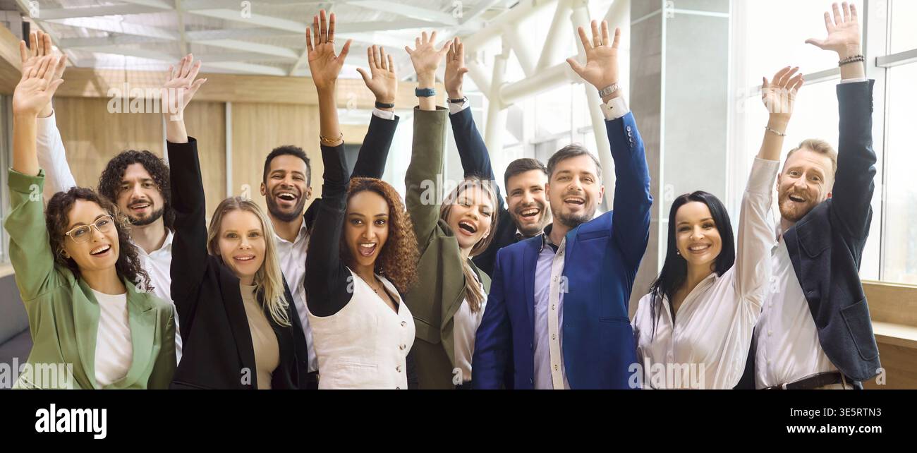 Vielseitiges Geschäftsteam feiert Erfolg mit erhobenen Händen in modernen Büros Stockfoto