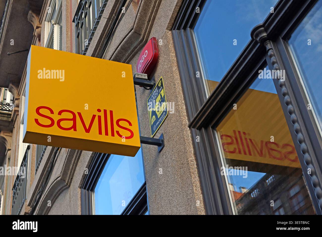 Savills Immobilienbüro-Logo auf einem Gebäude im Stadtzentrum von Porto, Portugal, mit gelbem und rotem Außenlogo des Unternehmens. Stockfoto