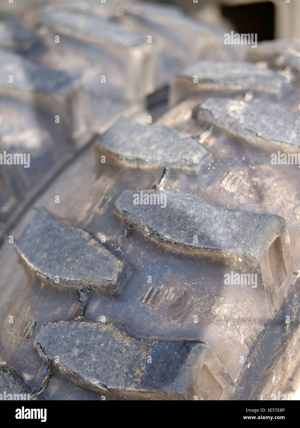 Reifenprofil für schwere Maschinen mit extremer Nahaufnahme, massive Gummistollen, Details für Industriereifen im Gelände, robuste Räder für Baufahrzeuge, verschlissene Stockfoto