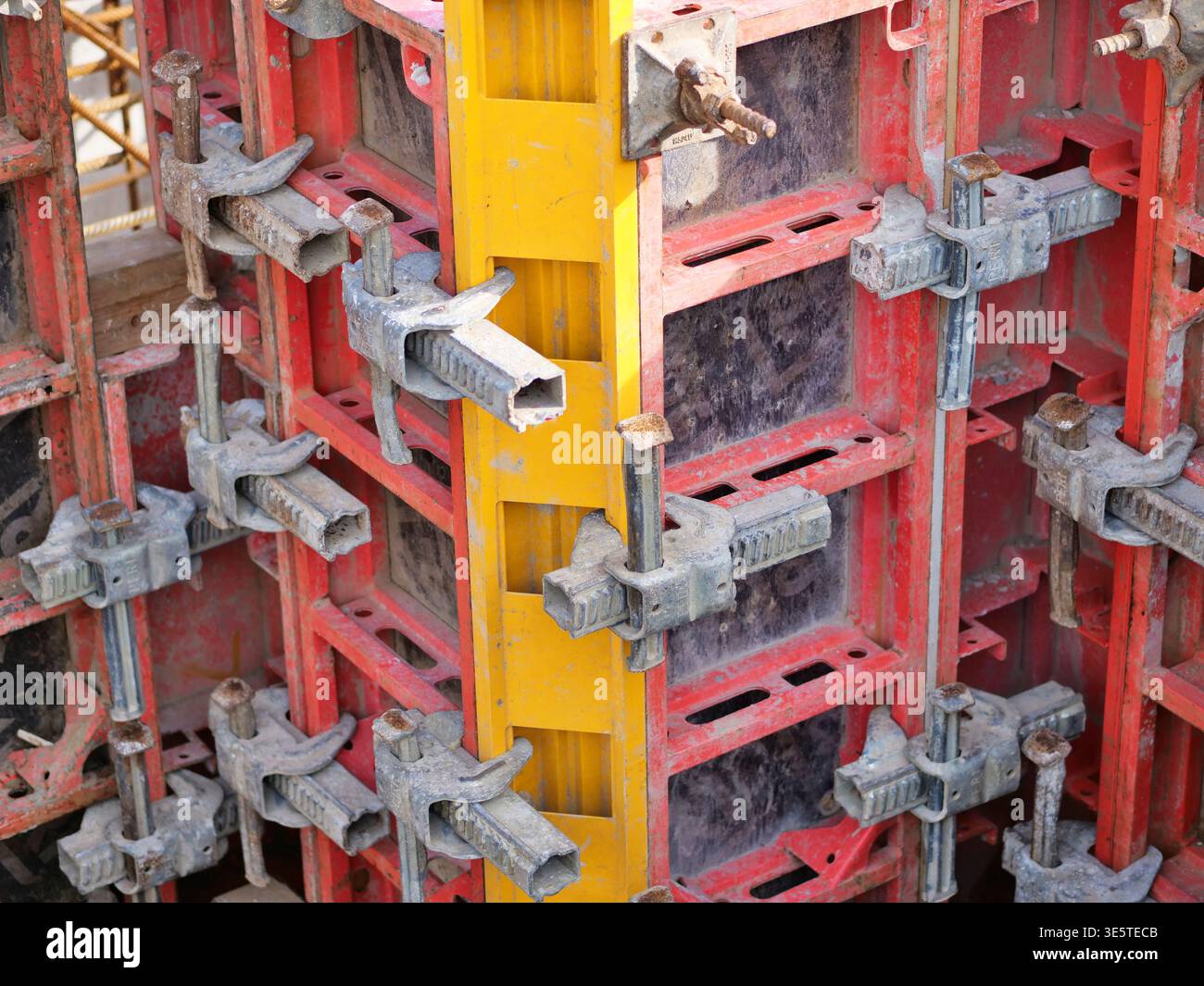 Industrielle Betonschalung, rote und gelbe Schalungsplatten aus Stahl, Nahaufnahme von Hochleistungs-Metallklemmen und Gerüstverbindern, Profi Stockfoto