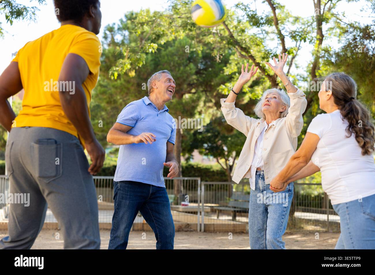 Alte multinationale Menschen spielen Volleyball-Aktivität auf einem Sommerspielplatz für Sport im Frühling draußen Stockfoto