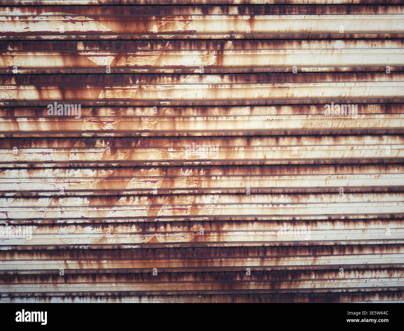 Eine verwitterte und rostende Metalltür mit starker Korrosion und industrieller Textur in einer städtischen Umgebung Stockfoto