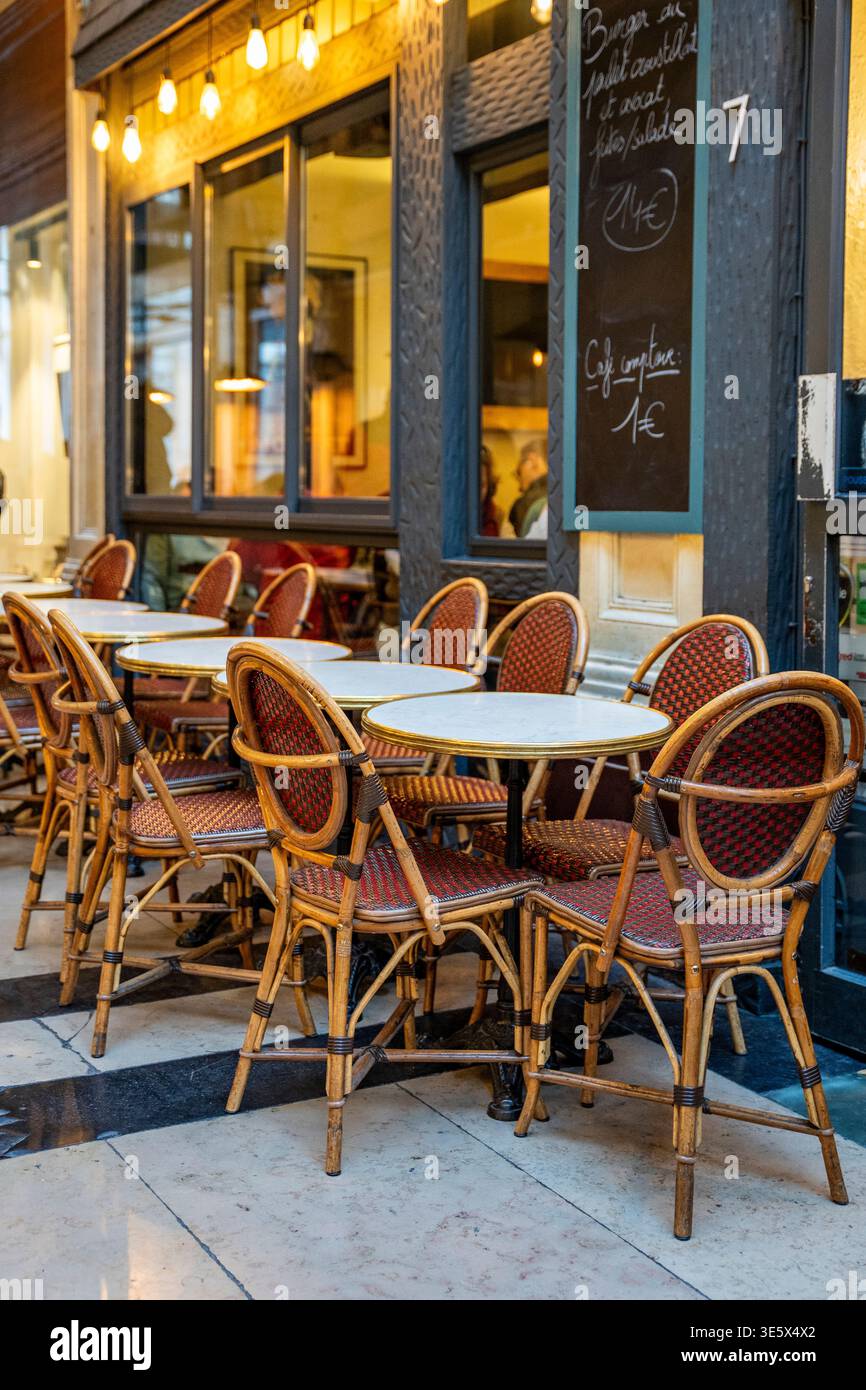 Kleine Bistrotische entlang eines stimmungsvollen Korridors einer historischen Pariser überdachten Passage in Paris, Frankreich. Stockfoto