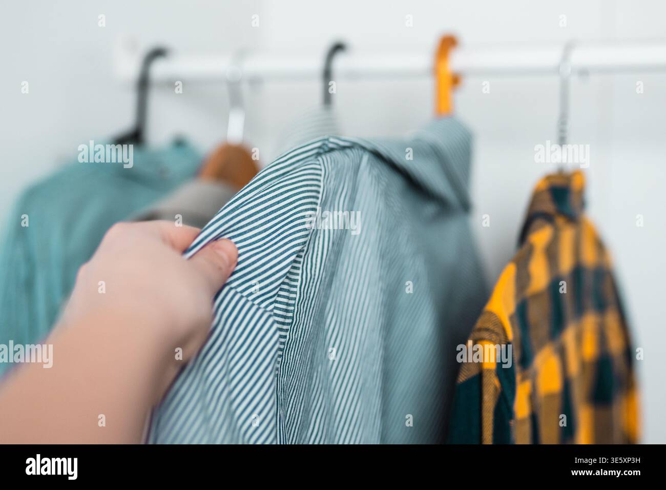 Reihe klassischer Herrenhemden, die an Kleiderbügeln hängen, in einem modernen, organisierten Kleiderschrank und einem ordentlichen Aufbewahrungskonzept für Kleidung. Stockfoto