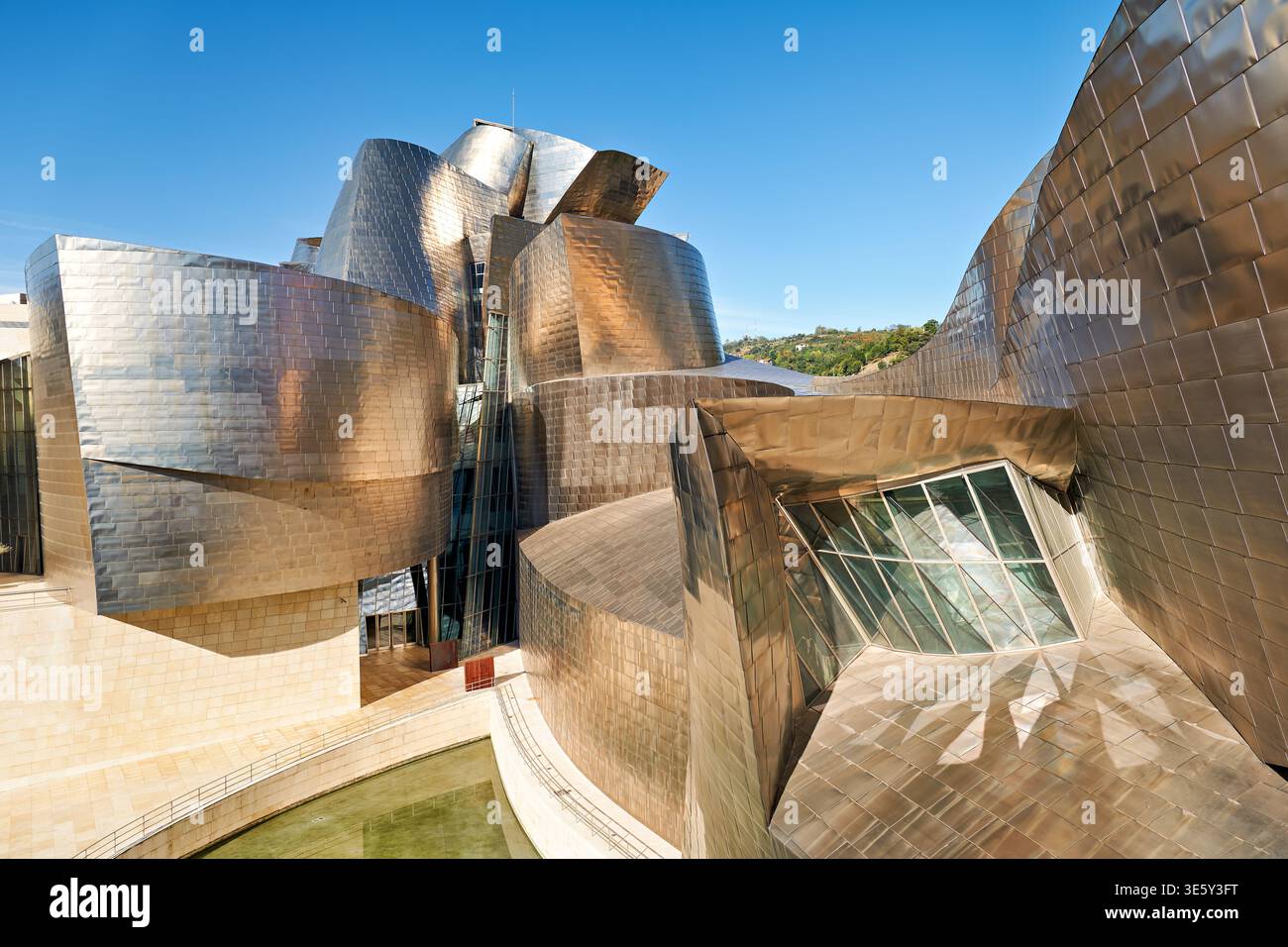 Besucher erkunden das Guggenheim Museum in Bilbao. Die Struktur zeigt modernes Design mit reflektierenden Oberflächen. Klares Wetter verbessert die Sicht. Stockfoto