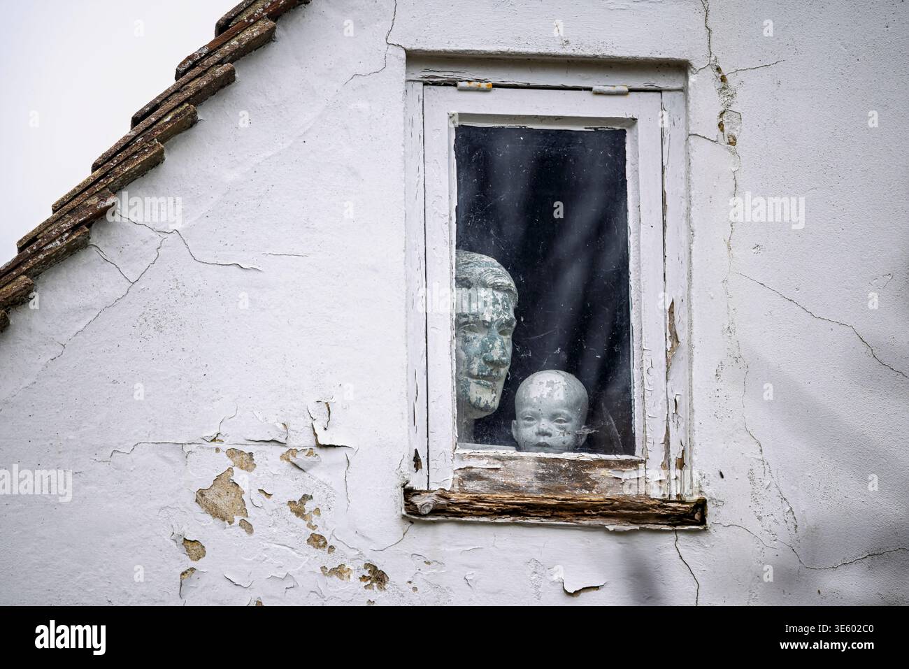 Erwachsene und kleine Steinköpfe, die am 31. März 2026 aus dem verrotteten Fenster in Pevensey, East Sussex, Großbritannien, blicken Stockfoto