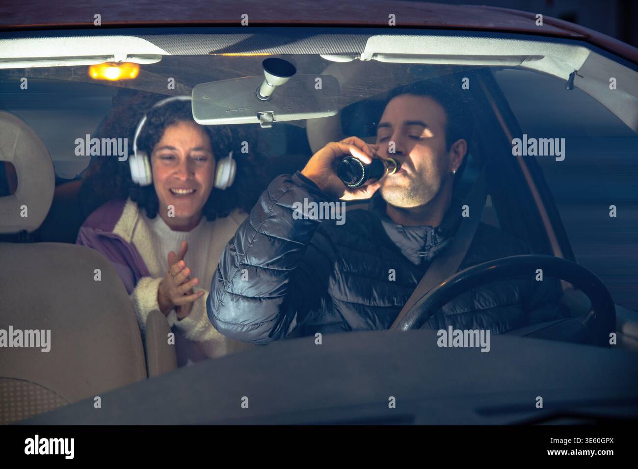 Fahrer trinkt Bier, während der Beifahrer glücklich zusieht Stockfoto