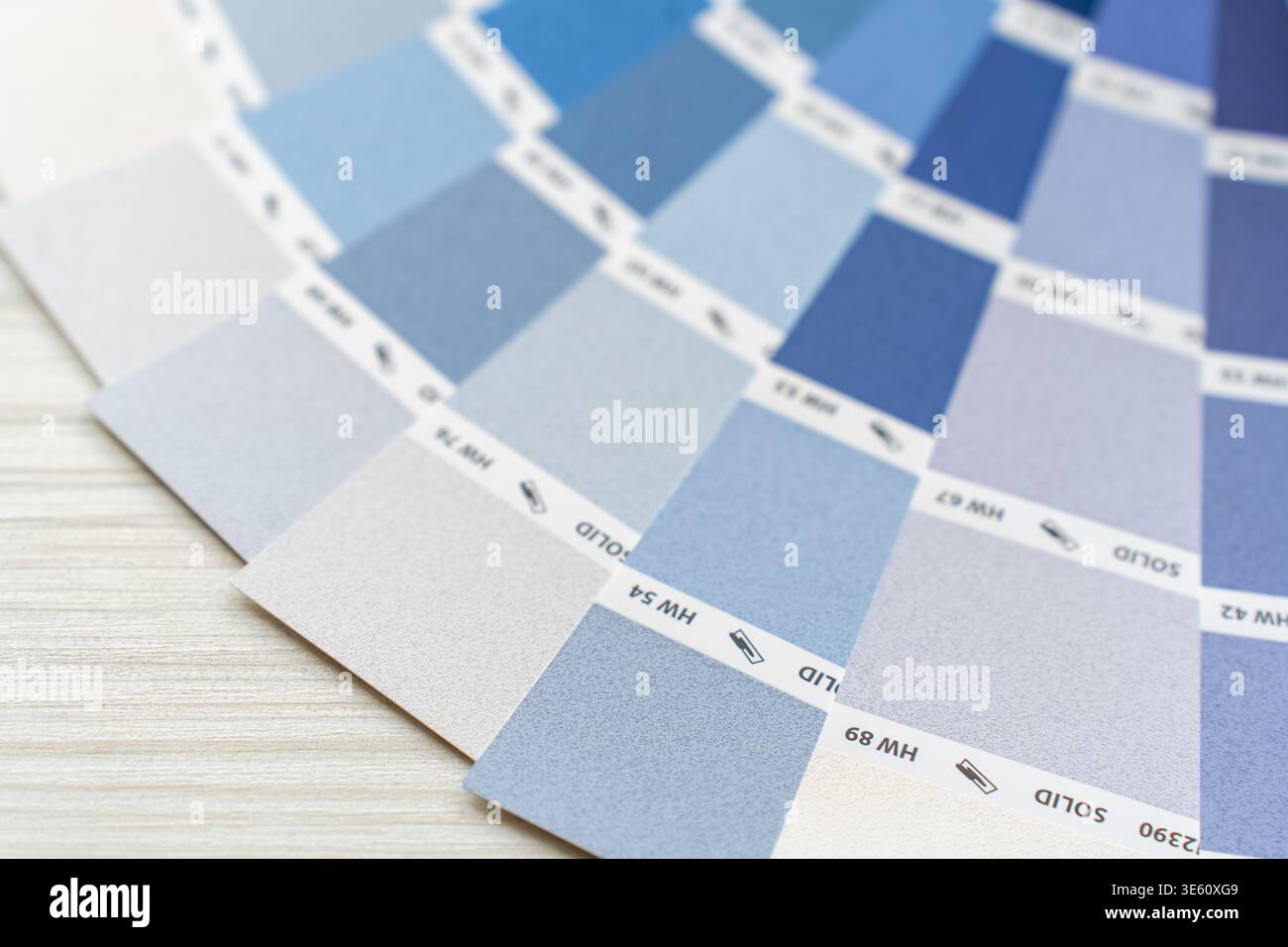 Eine umfassende Farbpalette zeigt eine Reihe von Blau- und Grautönen, die sich über eine helle Holzoberfläche ausbreiten. Jedes einzelne Farbfeld zeigt ein d Stockfoto