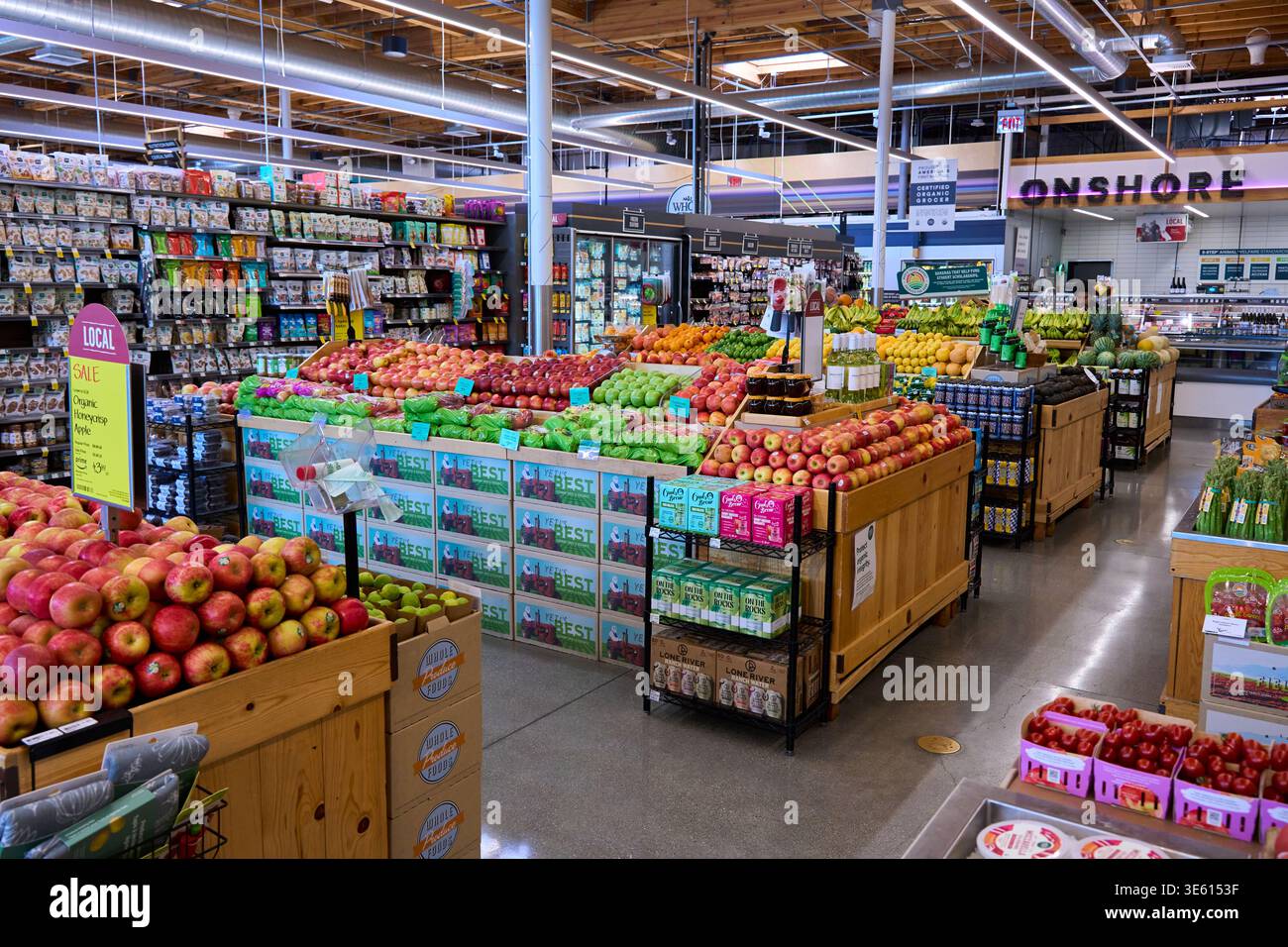 Das Innere eines modernen Bio-Lebensmittelgeschäfts mit frischem Obst und Gemüse. Große Auswahl an Äpfeln, Zitrusfrüchten und lokalen Produkten in Regalen. Stockfoto