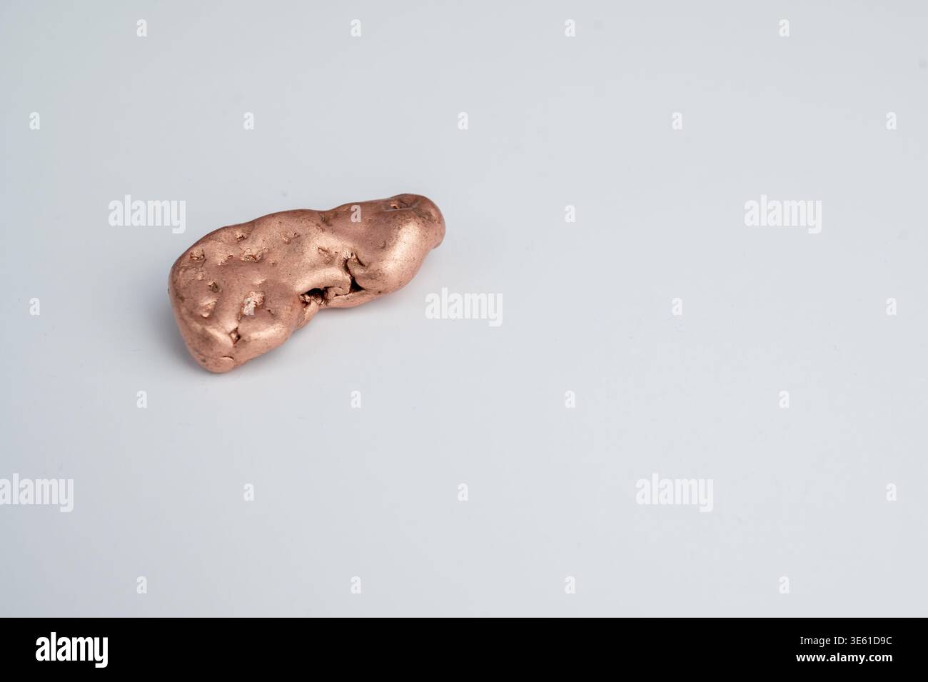 Kupfernugget liegt auf einer weißen Oberfläche auf Stockfoto