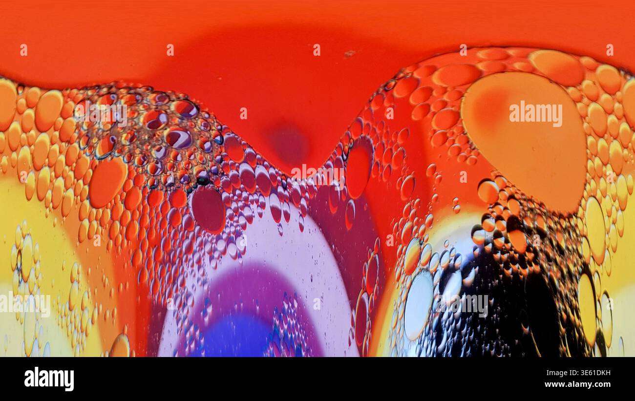 Öltropfen in Wasser bilden abstrakte Muster mit lebhaften Farben und Blasen Stockfoto