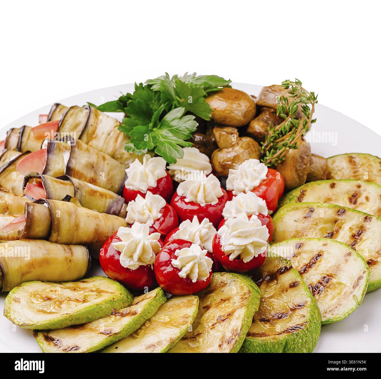 Speisen, Eine lebendige Auswahl an gegrillten Zucchini, Auberginen-Brötchen, gefüllten Kirschtomaten mit cremiger Füllung und sautierten Pilzen auf einem Rind Stockfoto