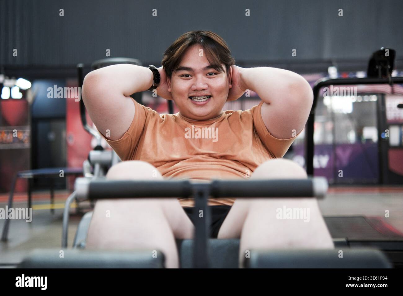 Übergewichtiger Mann, der Sit-ups während eines Workouts im Fitnessstudio macht. Konzentrieren Sie sich auf Gewichtsverlust, Kernkraft und gesunde Lebensweise. Das Konzept der Fitness Challengeng Stockfoto