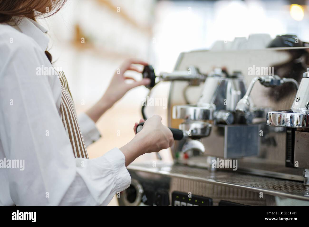 Ein Barista oder Café-Mitarbeiter, der eine Espressomaschine verwendet, um Kaffee in einem Café zuzubereiten. Die Szene zeigt das Engagement, die Präzision und die Kundenorientierung Stockfoto