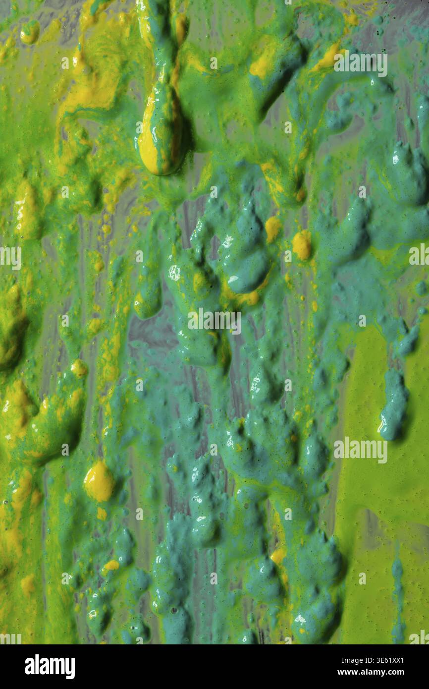 Hellgrüne und gelbe Farbspritzer bedecken die Oberfläche. Die Farbe ist dick und hat eine glänzende Textur, die ihr einen einzigartigen Look verleiht. Die Spritzer sind Stockfoto