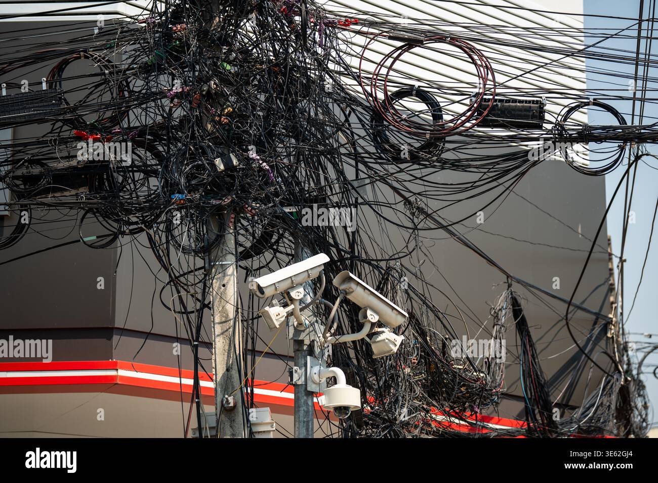 Verwirrte Stromkabel und Datenkabel am Pol, asiatisches Wahrzeichen an der Straße in der Stadt. Stockfoto