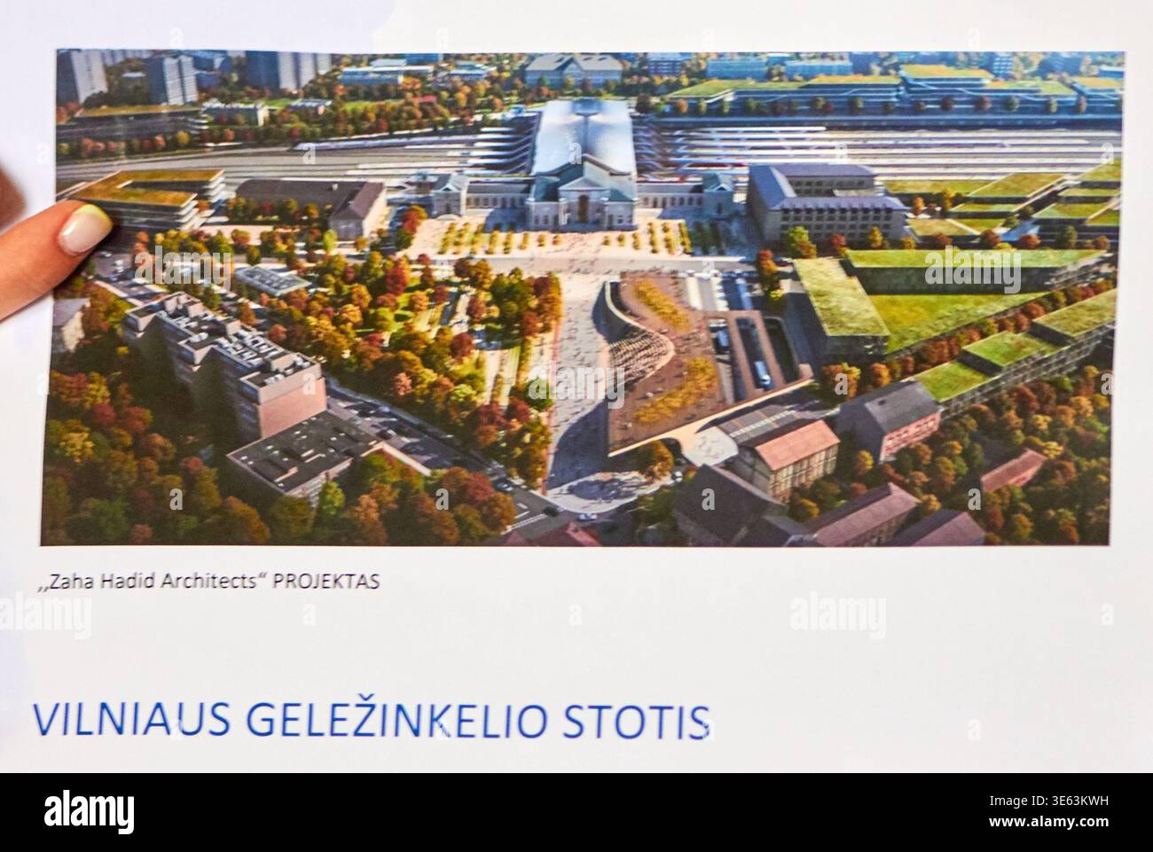 Die Hand einer Person mit hellem nagellack hält ein bedrucktes Architekturbild oder Poster, das eine Luftaufnahme des vorgeschlagenen Vilnius zeigt Stockfoto