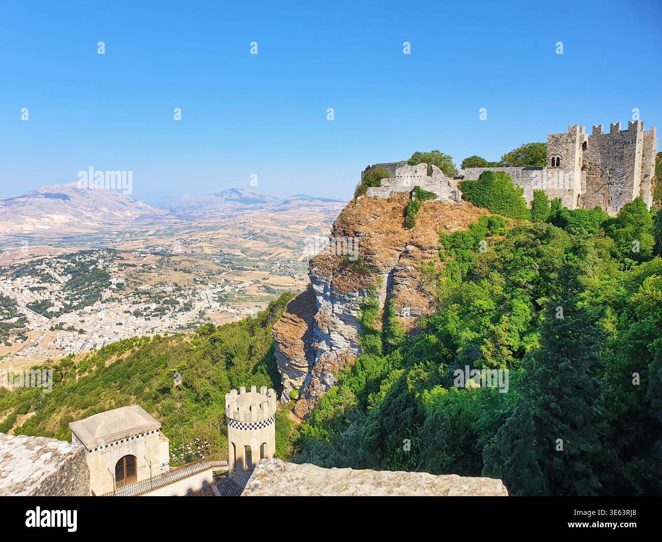 Eine mittelalterliche Steinburg und Festung auf einer steilen Felsklippe, bedeckt von üppiger grüner Vegetation, mit Blick auf eine weite Panoramablick Stockfoto