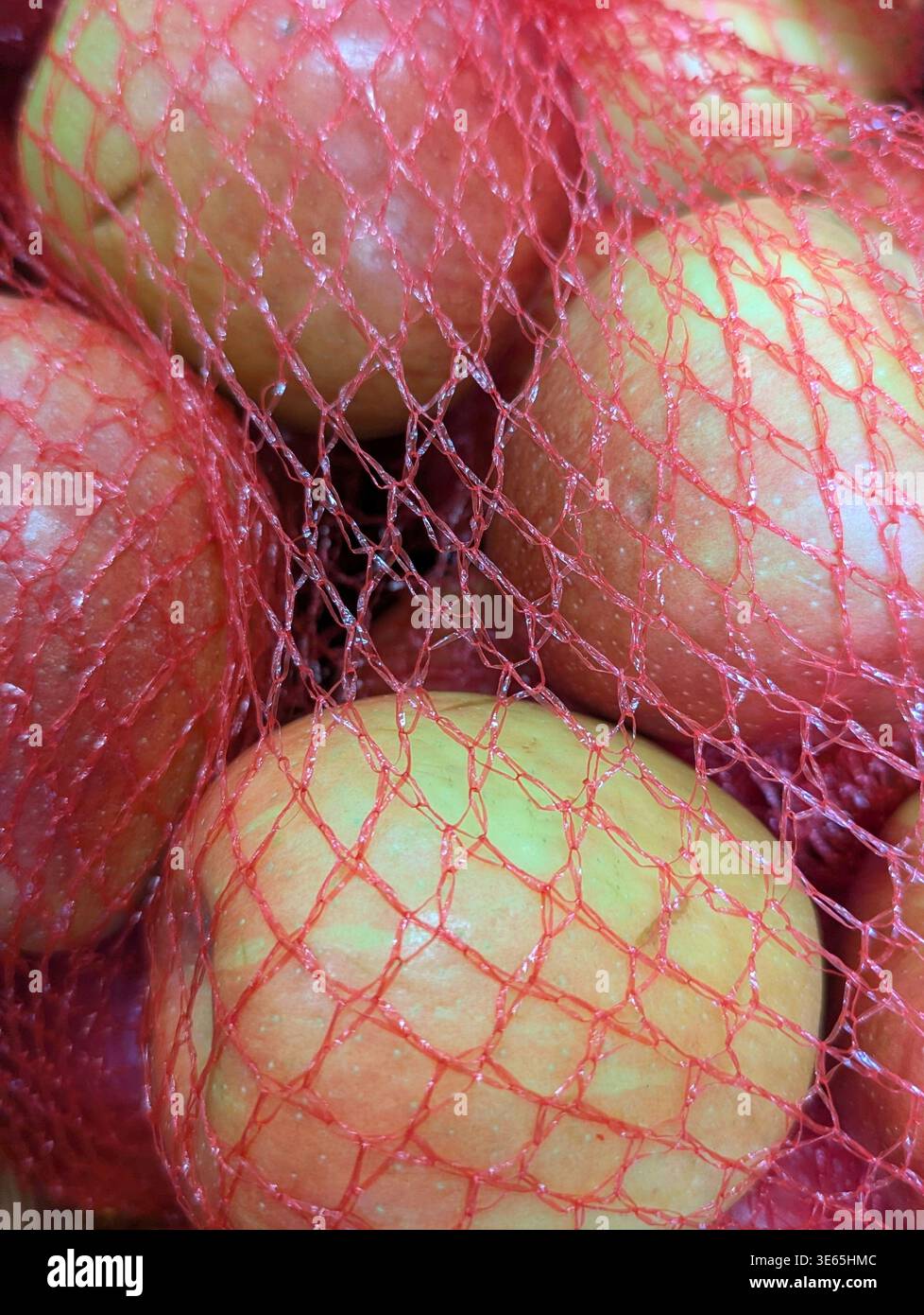 Close Up Äpfel – Rote Mesh-Tasche Mit Taubigen Häuten, Die Das Morgenlicht Einfangen, Leuchtenden Farbkontrast Zwischen Rot Und Hellgrün, Detailliertes Gewebtes Netz-Textu Stockfoto