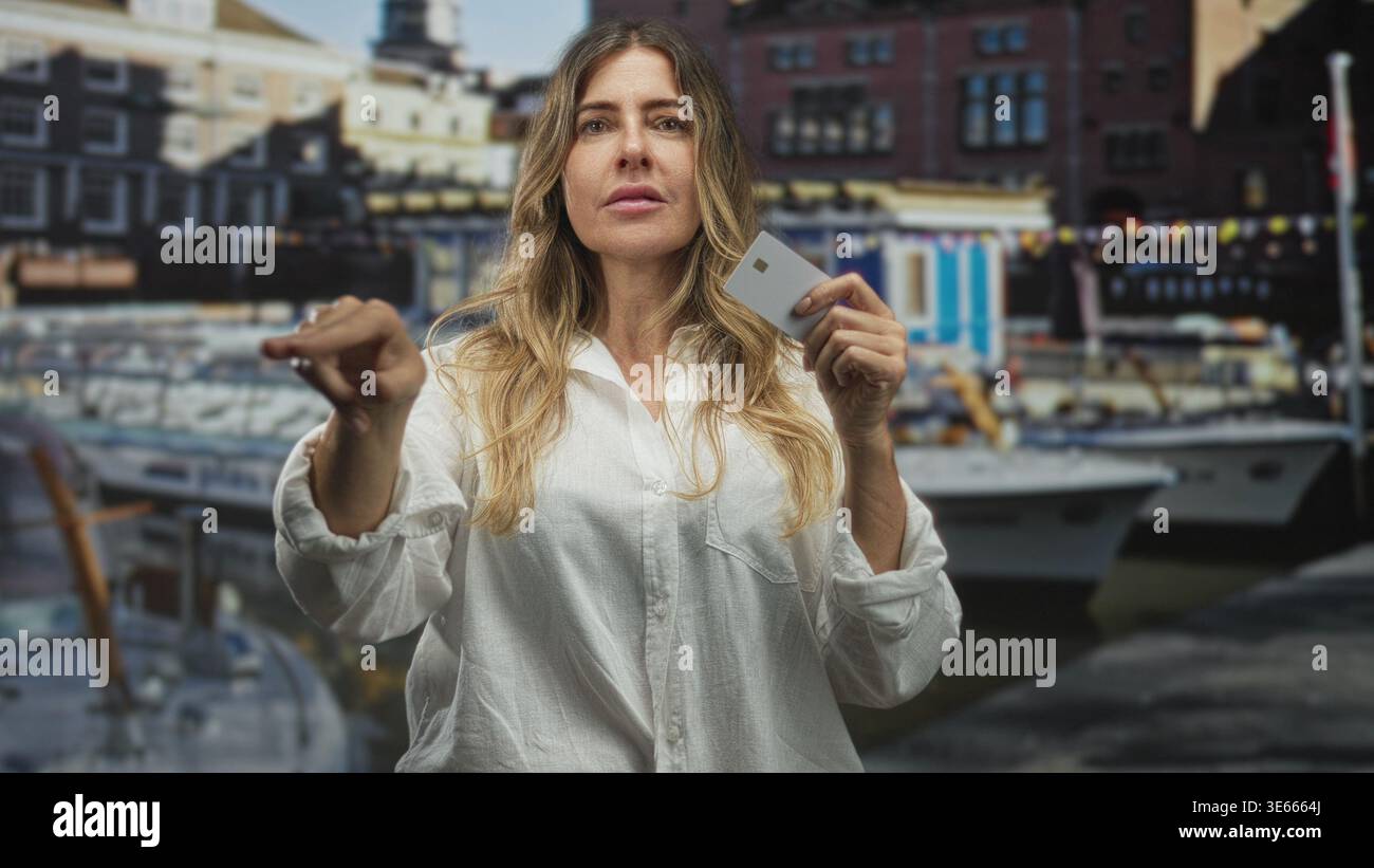 Frau, die eine Kreditkarte hält und mit dem Finger nach vorne zeigt, mit Booten am Hafen; Selbstvertrauen stärken. Stockfoto