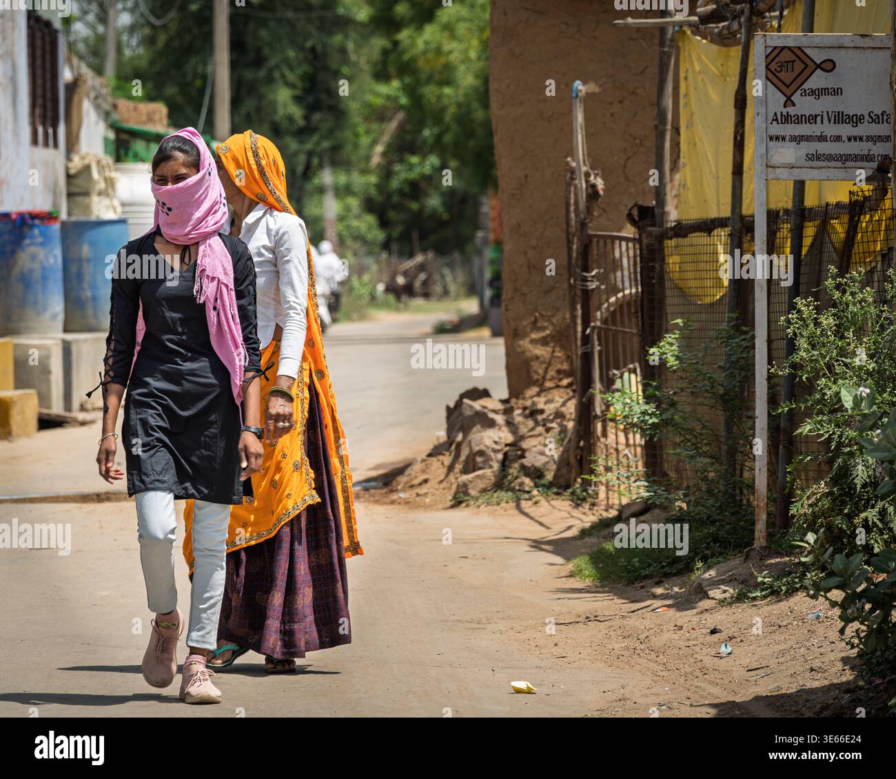 Abhaneri Village, Rajasthan, Indien--13. April 2023. Zwei Frauen laufen auf einer Landstraße im Dorf Abhaneri, Rajasthan, Indien. Man trägt ein traditionelles o Stockfoto