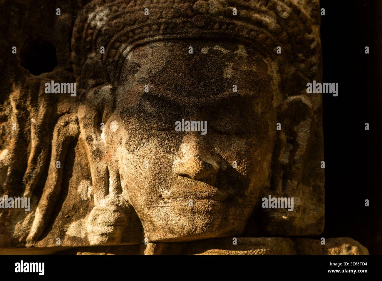 Altes Steingesicht mit feierlichem Ausdruck. Tief verschlissene Oberfläche erzählt Jahrhunderte von Geschichte. Warmes Licht hebt komplizierte Tempeldetails hervor. Myst Stockfoto
