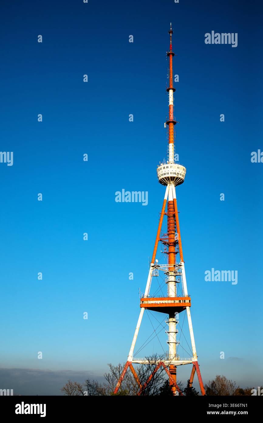 Vollständige vertikale Ansicht eines rot-weißen Senderturms, der bei Tageslicht hoch steht. Stockfoto