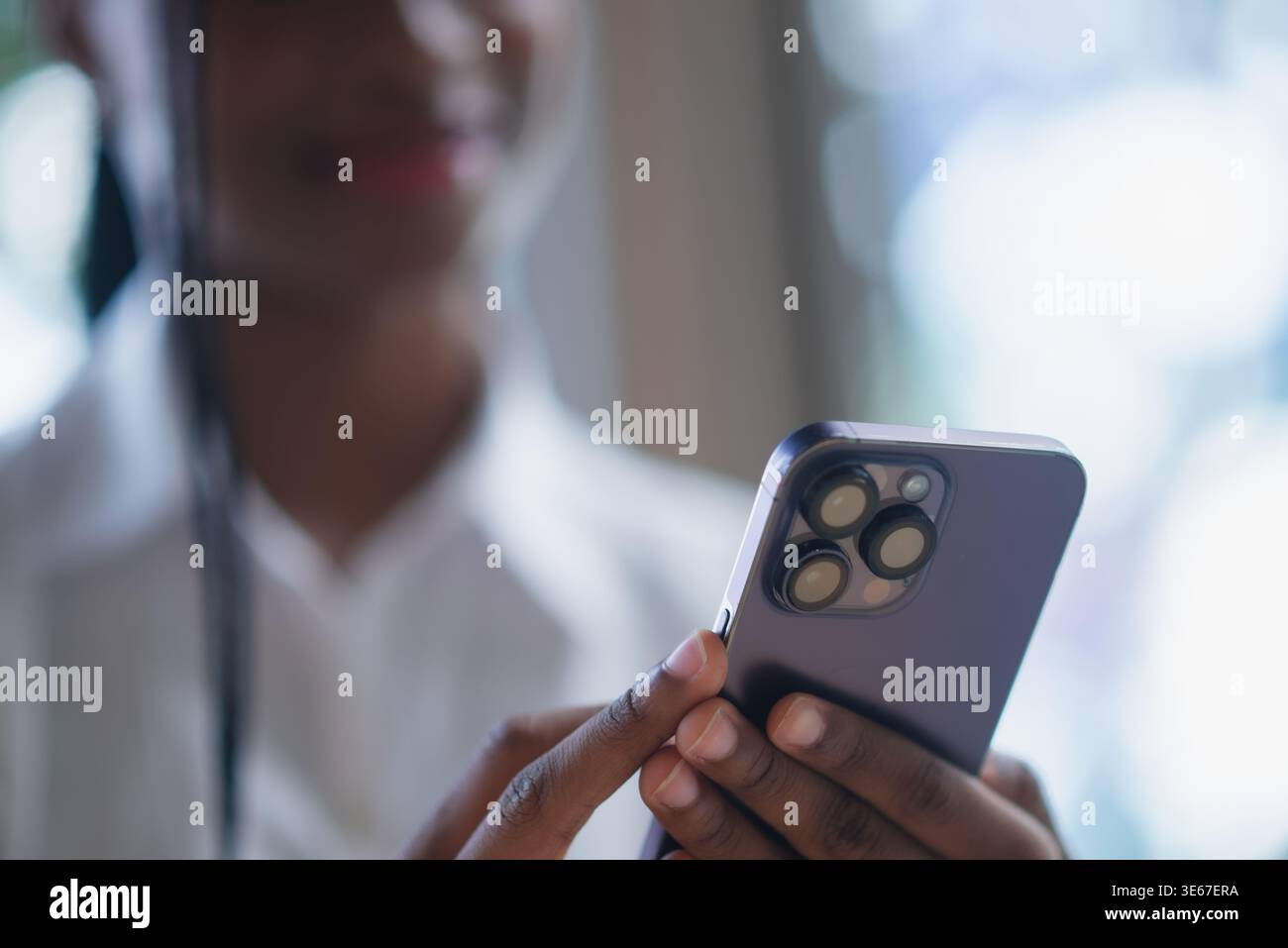 Nahaufnahme einer jungen Schwarzen Frau mit Smartphone und Finger auf dem Bildschirm bei weichem Tageslicht. Browsen in mobilen Apps, Touchscreen-Technologie, Online-Kommunikation Stockfoto