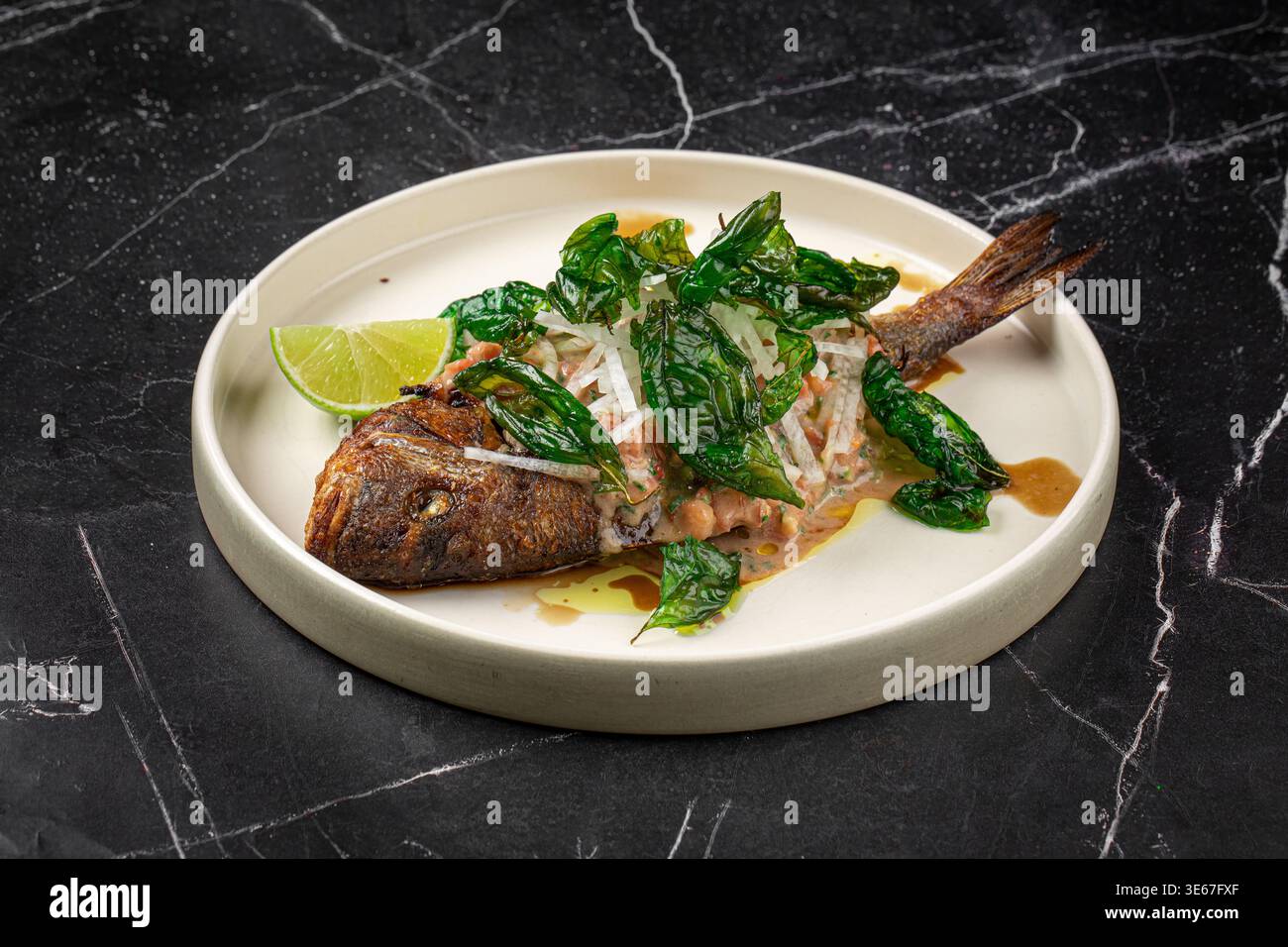 Gegrillter Fisch mit Kräutern und Limette auf Teller Stockfoto