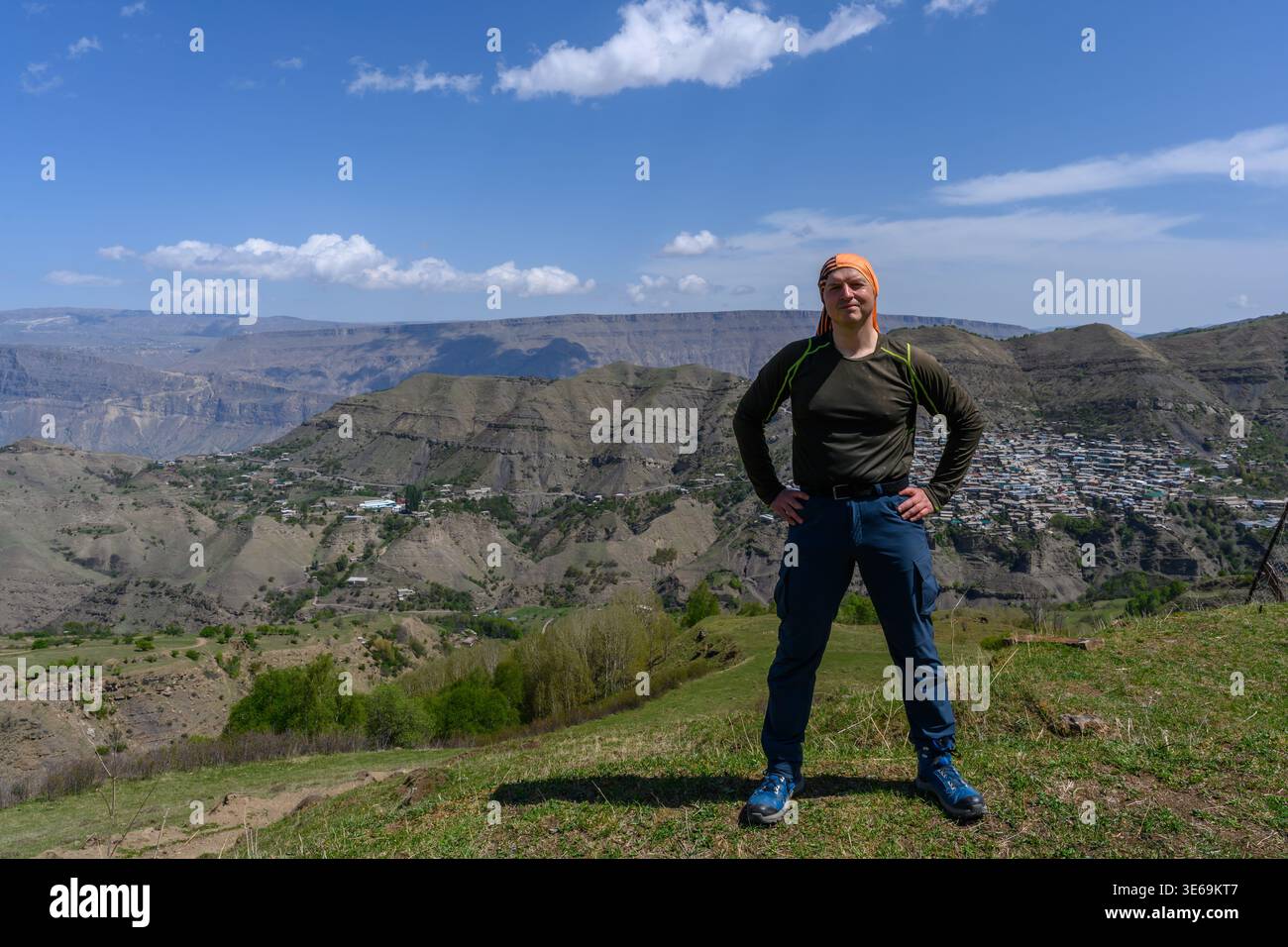 Ein starker Mann steht auf einem Berg vor einer malerischen Landschaft, während er an einem bewölkten Frühlingstag in Dagestan wandert. Bergwandern. Stockfoto