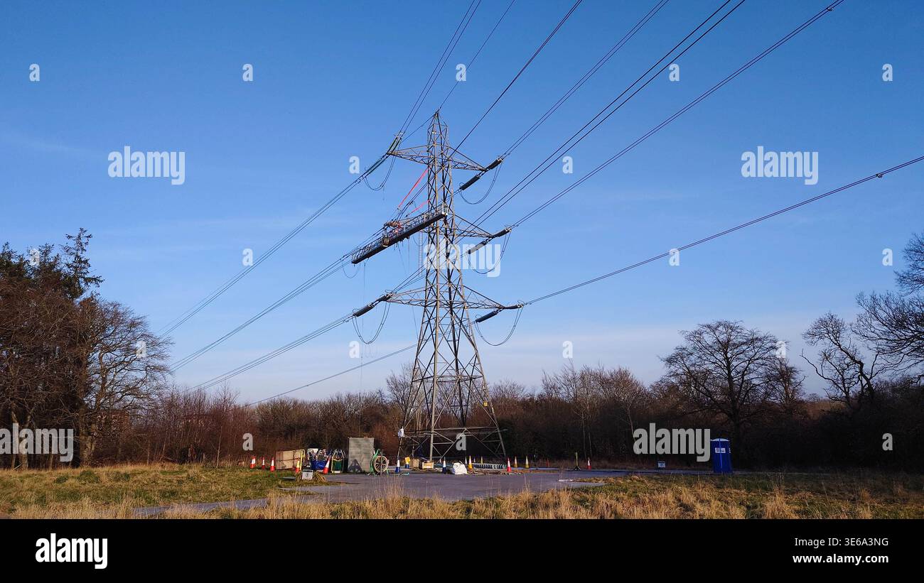 igh-Spannungs-Übertragungsturm mit abgehängter Wartungsplattform und Instandhaltungsarbeiten unter dem Turm Stockfoto