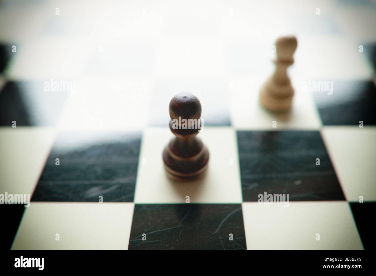 Nahaufnahme hölzerner Schachfiguren auf einem Brett, die ein stehendes Duell, ein gefallenes Paar und eine chaotische Endspielszene zeigen. Horizontale Studioaufnahme im Innenbereich. Stockfoto