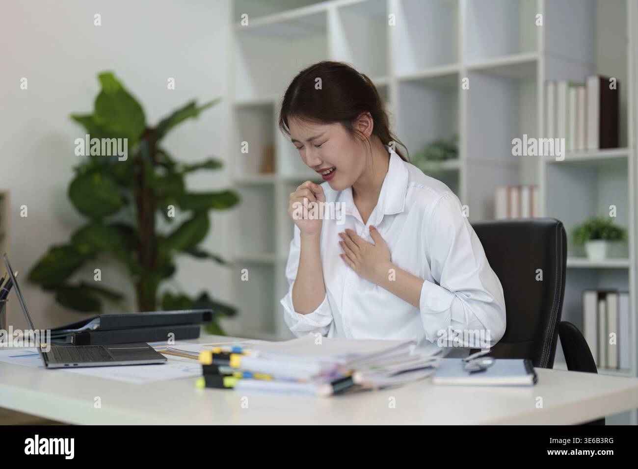 Eine junge Frau drückt ihre Emotionen aus, während sie an ihrem Schreibtisch sitzt und die Herausforderungen zeigt, die es mit dem Umgang mit Stress in einem beruflichen Umfeld zu tun hat Stockfoto