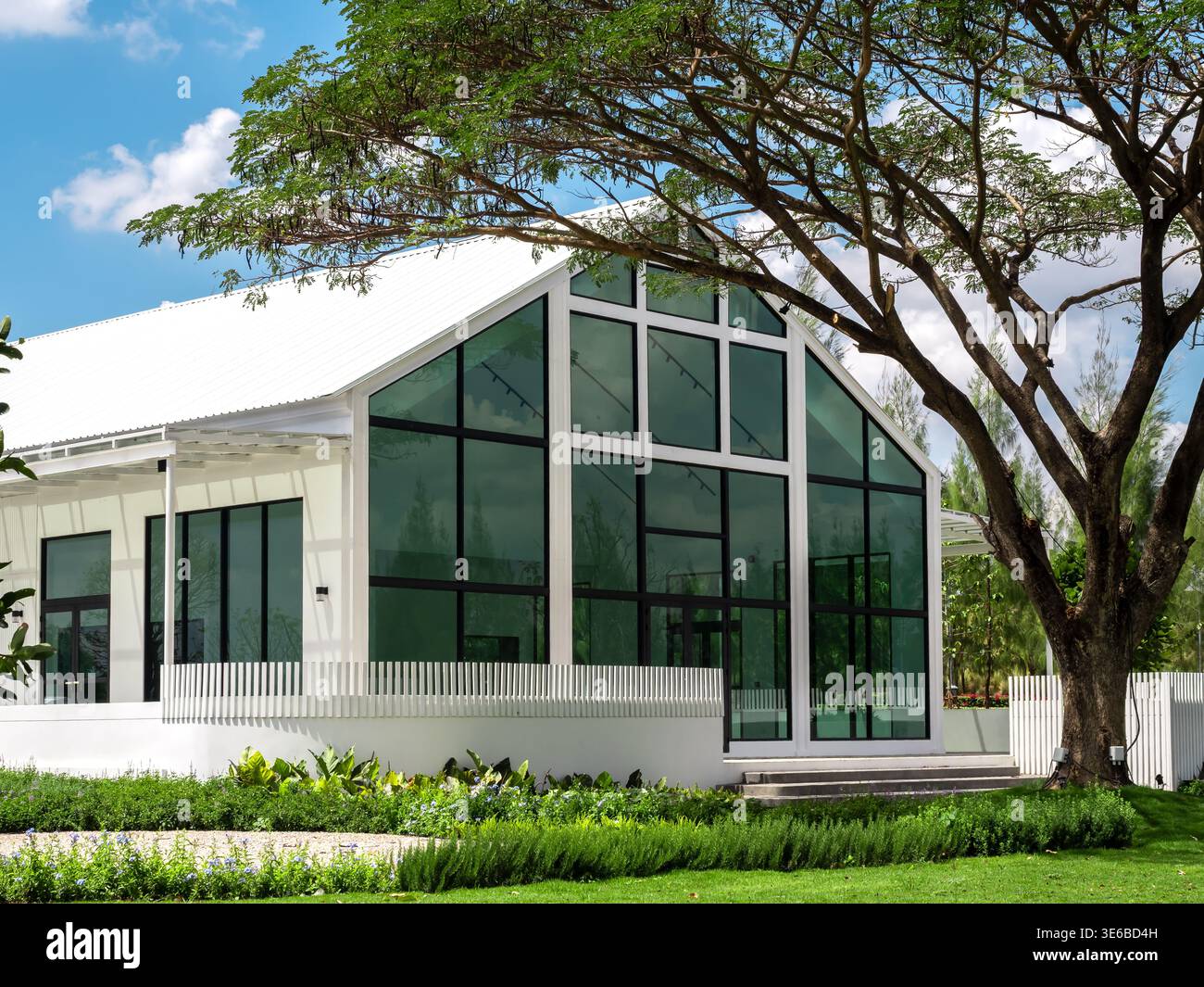 Modernes Glashaus umgeben von grünen Bäumen und Garten. Nachhaltiges Wohnen, umweltfreundliche Architektur, energieeffizientes Wohndesign, moderne Residenti Stockfoto