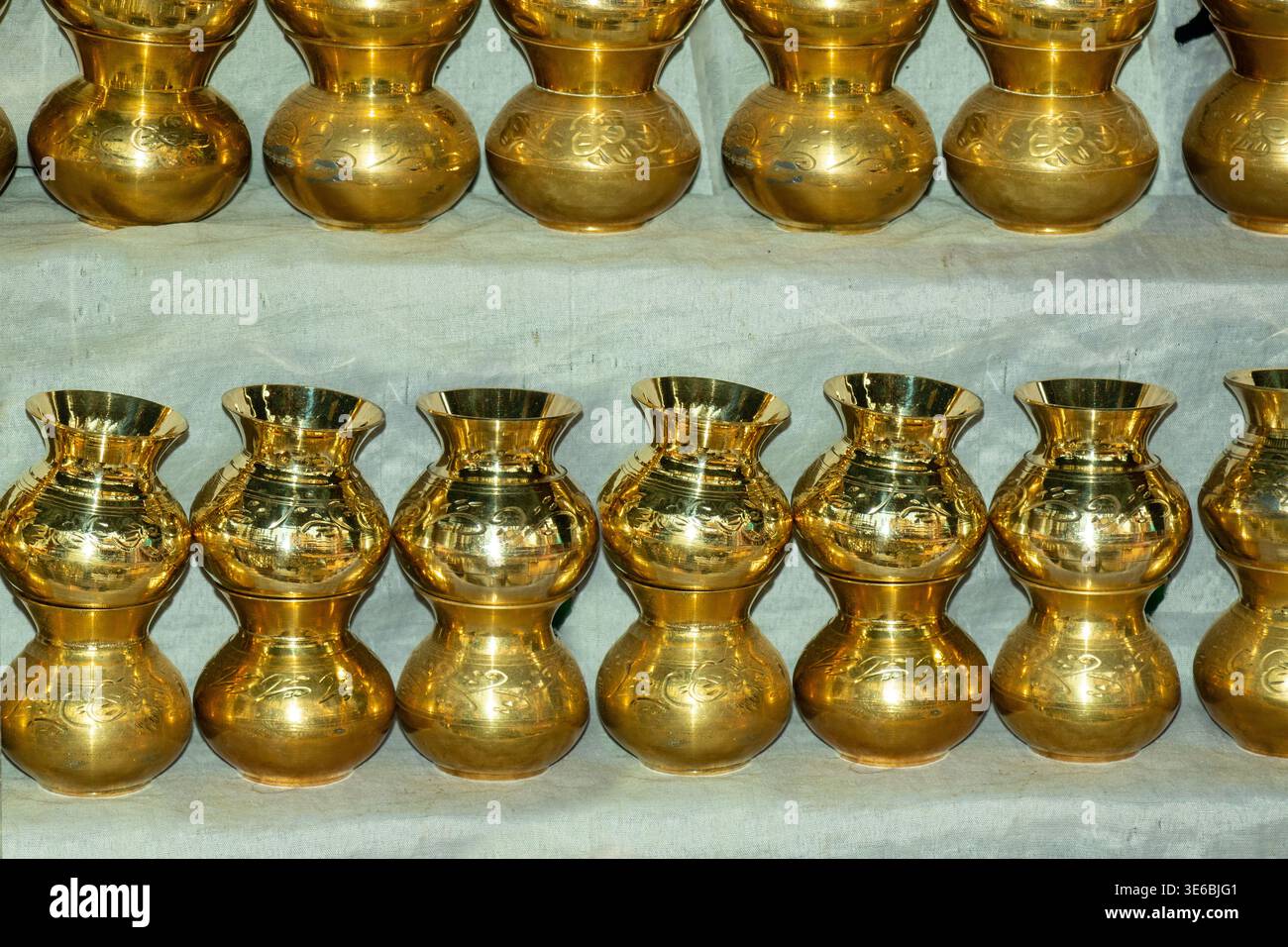 Traditionelle Lota kalash-Töpfe aus Messing, handgefertigte goldene indische Ritualwassergefäße mit Blumenmotiven. Perfekt für religiöse Hindus und festliche Veranstaltungen Stockfoto