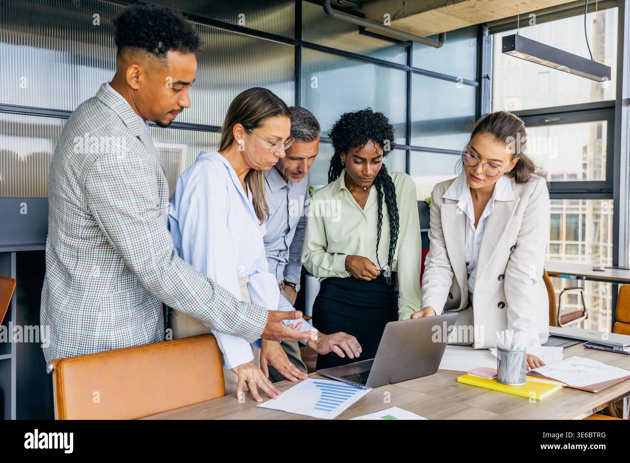 Ein Team mit unterschiedlichen Hintergründen bespricht Drahtmodelle in einem freigegebenen Arbeitsbereich Stockfoto