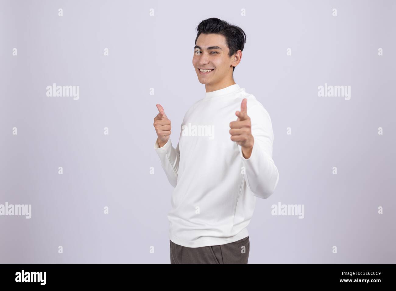 Fröhlicher junger Mann, der mit beiden Fingern auf die Kamera zeigt Stockfoto
